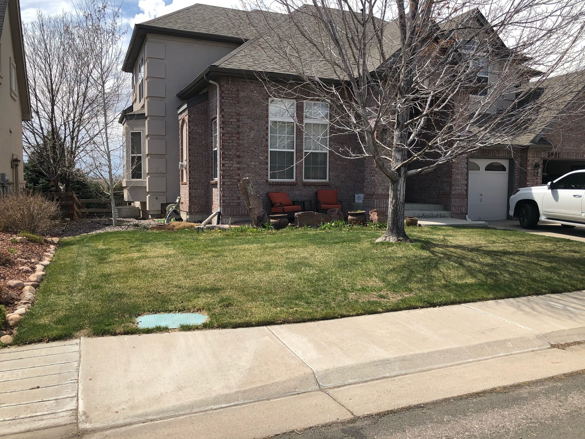 A brick house with a front yard of turf grass, before its Xeriscape design